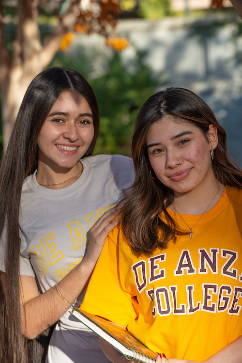 young woman in Villages T-shirt with De Anza pennant